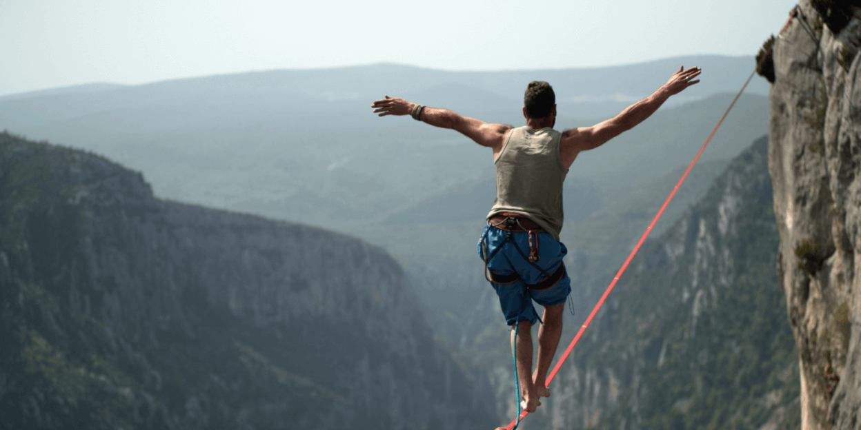 Photo of man crossing cliffs on a wire