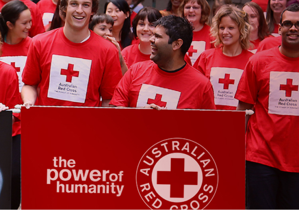 People in Red Cross shirt with banner in front of them