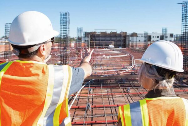 two construction workers surveying scene