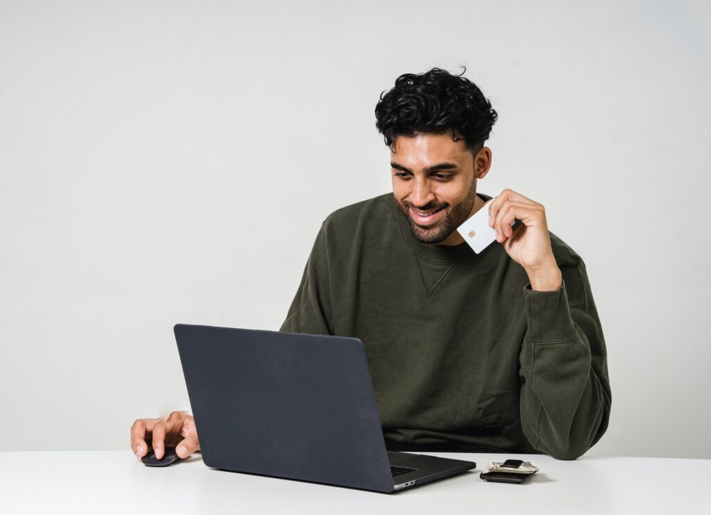Man smiling looking down at laptop with credit card in hand