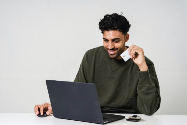 Man smiling looking down at laptop with credit card in hand
