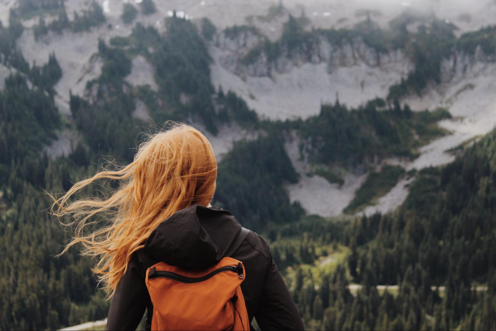 Woman with hair blowing in the wind looking at mountains