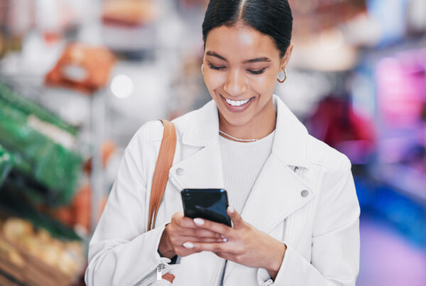 Women in retail store looking down at phone smiling