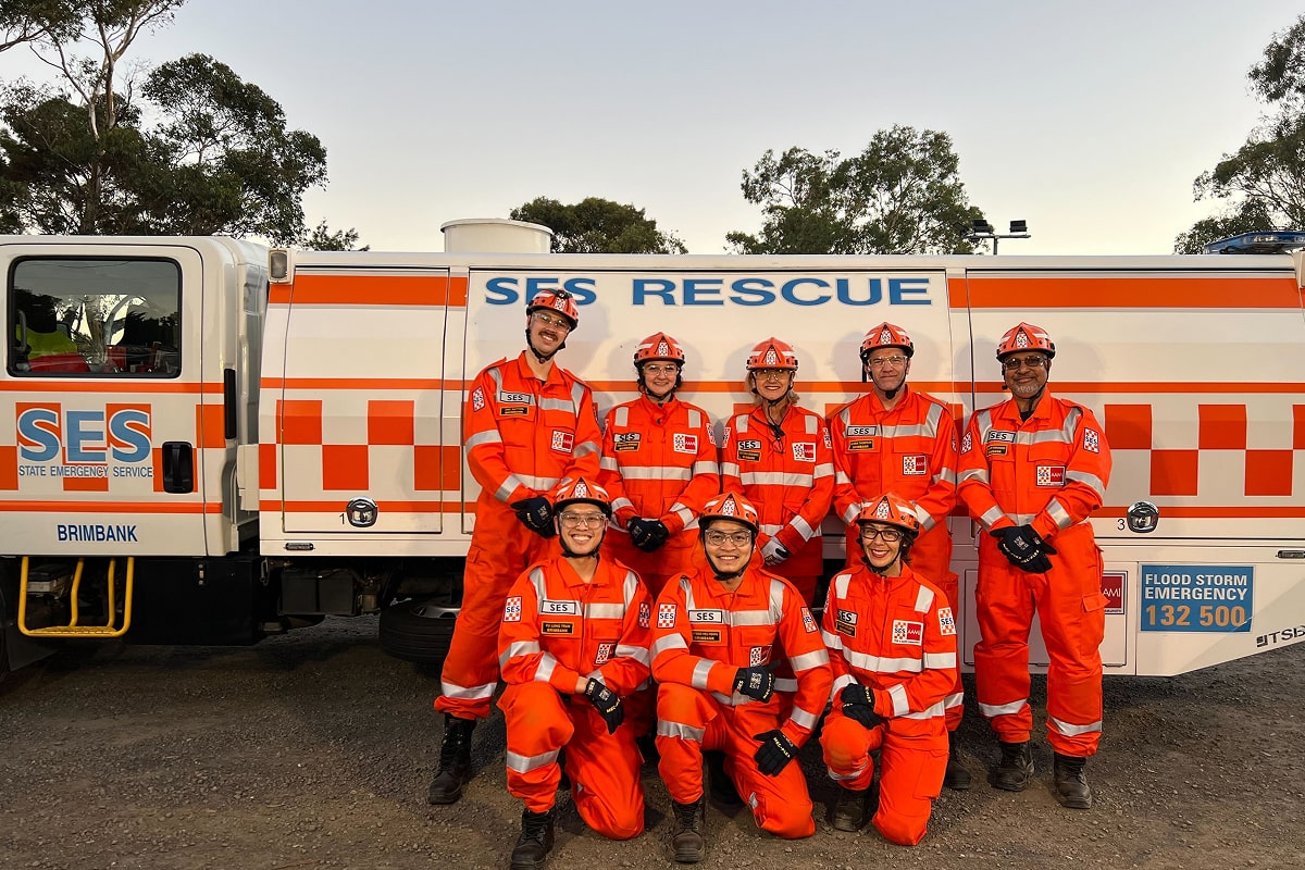 A group of Victorian SES workers posing in their uniforms in front of an SES truck.
